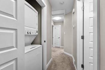 A hallway with white doors on both sides and a washer and dryer in the corner.